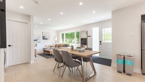 Eine moderne Küche mit Essbereich, mit einem Holztisch, grauen Stühlen und einem eingebauten Backofen.