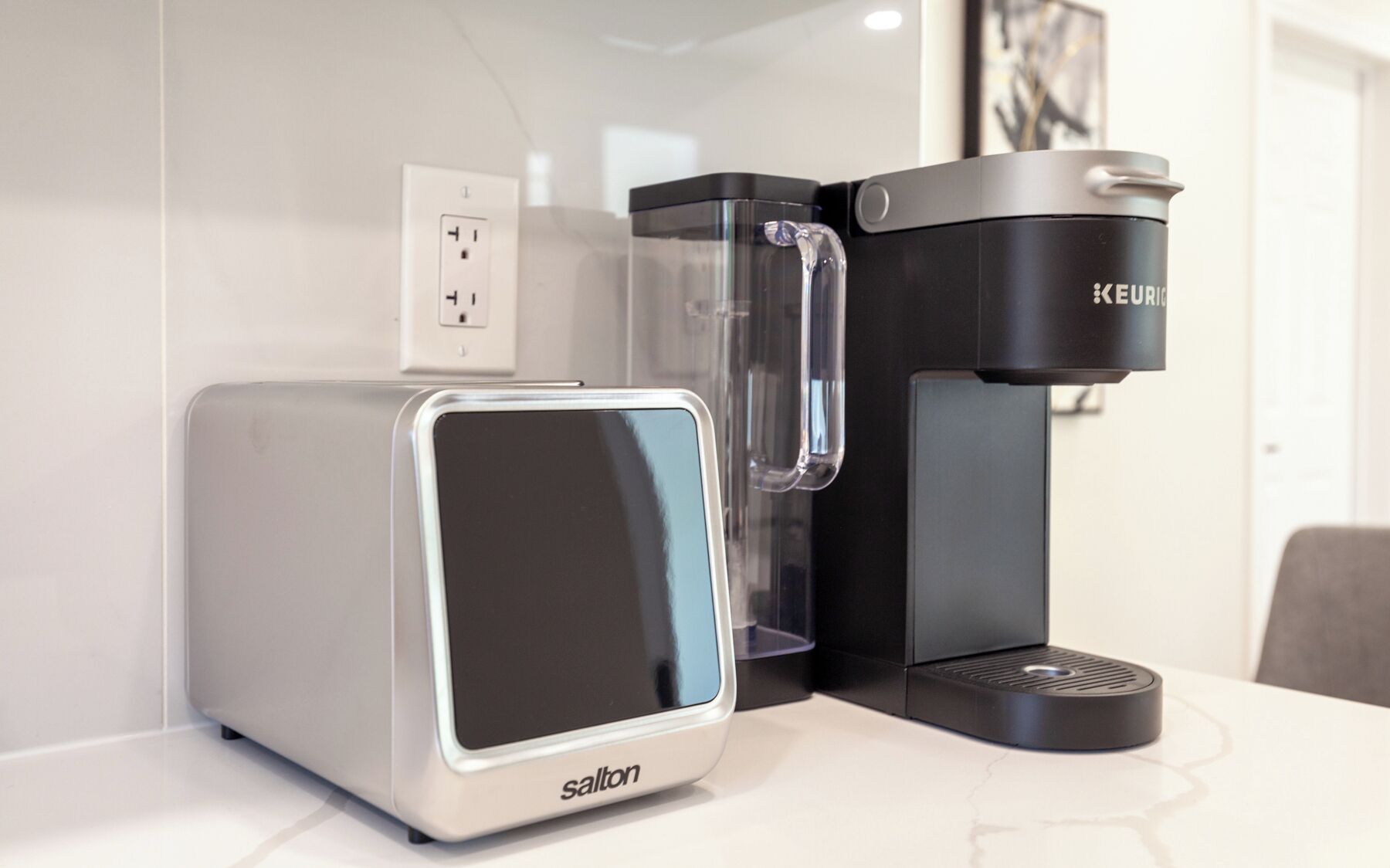 Eine moderne Küche mit glänzender Arbeitsplatte, einer Kaffeemaschine und einem Toaster.