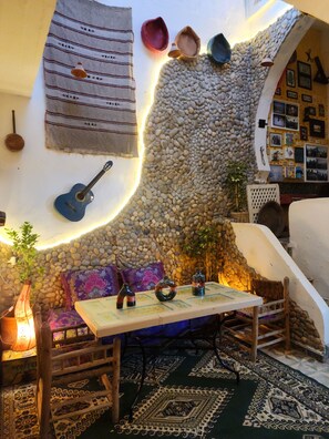 Un intérieur chaleureux avec un mur en pierre, une guitare et une table agrémentée d’objets décoratifs.