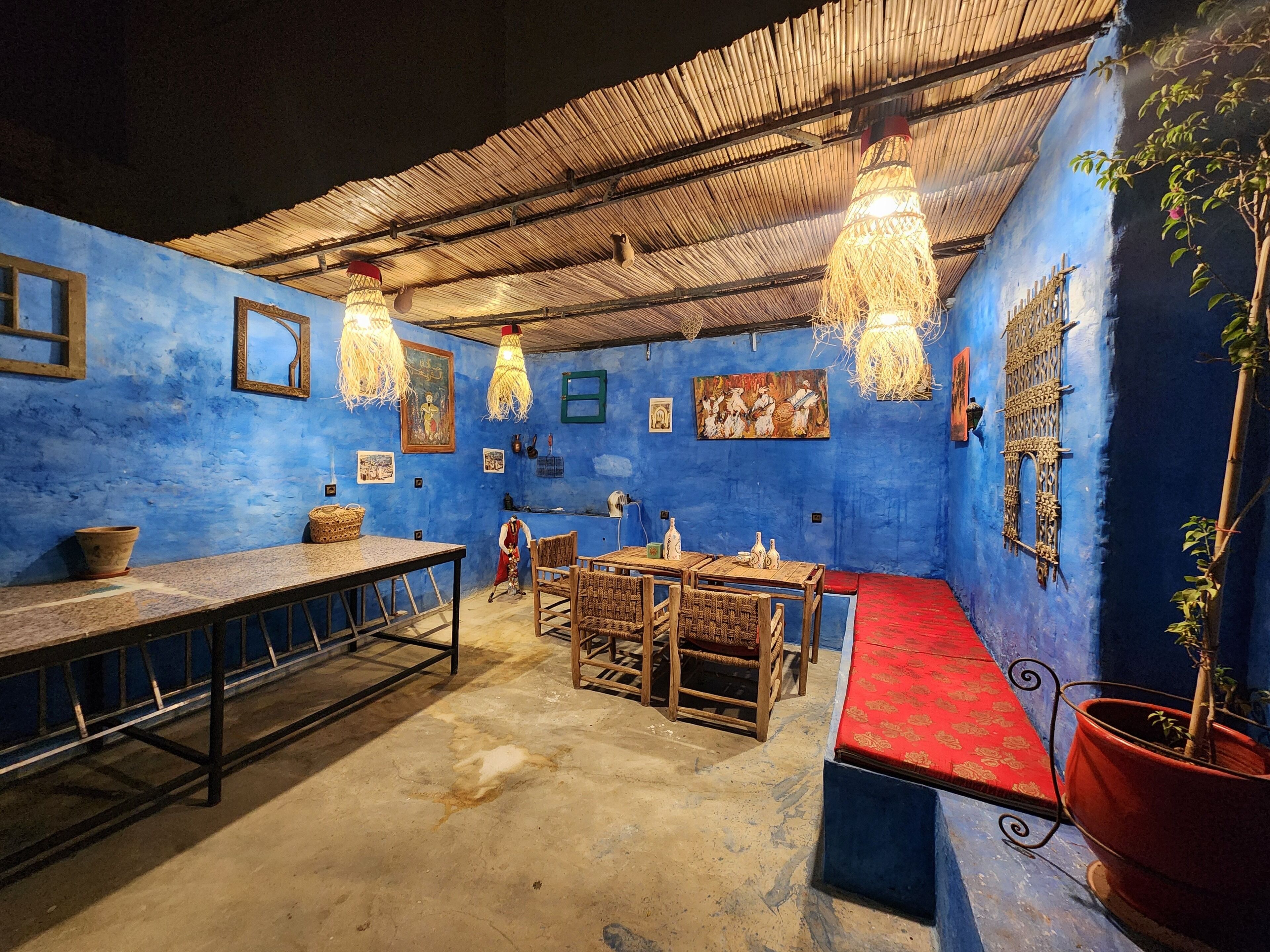A room with blue walls, a thatched roof, and a dining area with wooden furniture.