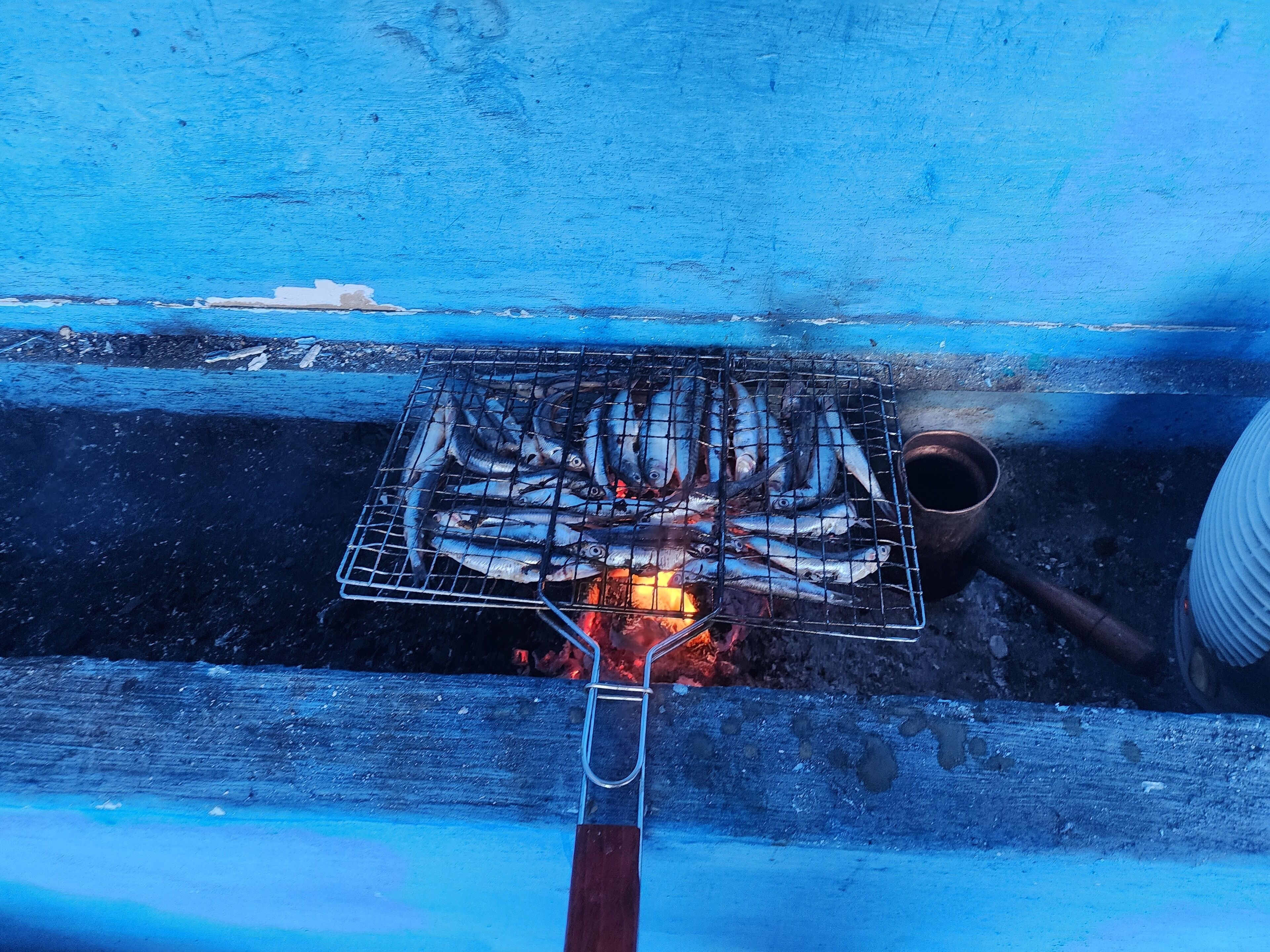 Ein Grill mit Fisch, der über offenen Flammen zubereitet wird.