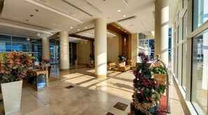 A spacious lobby with high ceilings, large windows, and a central Christmas tree.