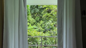 Ein Zimmer mit Blick auf einen Balkon und üppiges Grün.