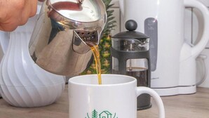 Une main verse du café dans une tasse ornée du logo d’Ashdene House.