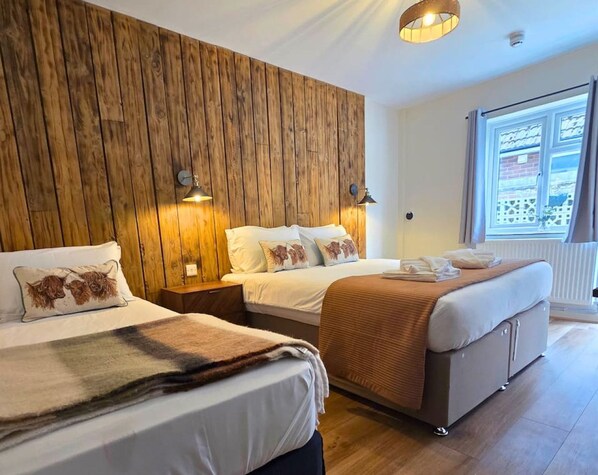 Habitación de hotel con dos camas, paneles de madera en la pared y un ventanal con vistas.