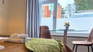 A hotel room with a bed, a table with a potted plant, and a view of the street outside. - Duke of the Pond - Room 1 - New Forest (Dibden Purlieu)