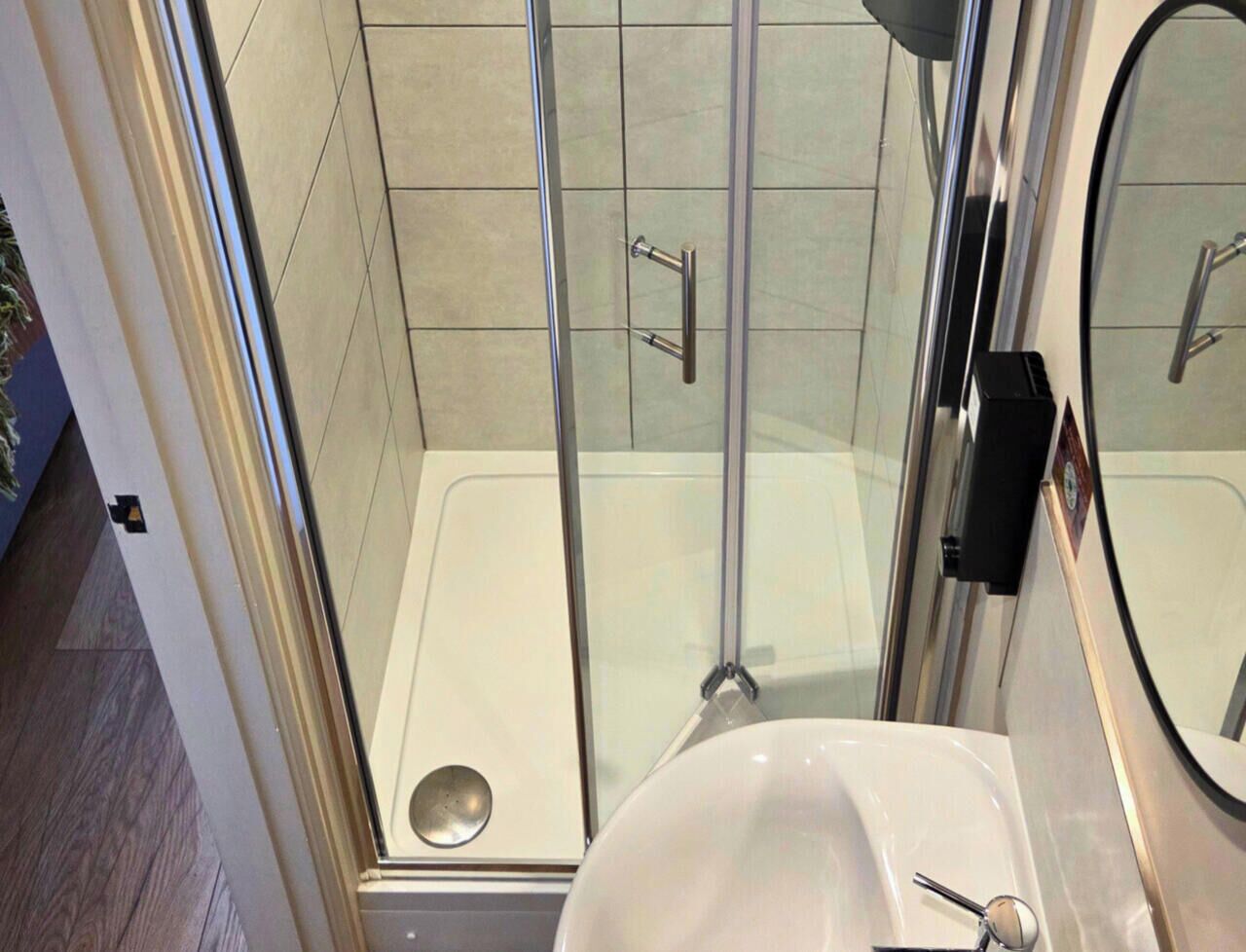 A bathroom with a glass shower enclosure, a white sink, and a mirror.