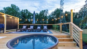 Eine Holzterrasse mit Whirlpool, Liegestühlen und einem Holzzaun.