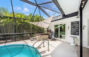 A pool area with a glass ceiling, a hot tub, and outdoor seating.