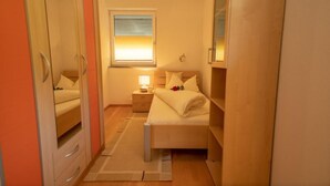 A bedroom with a bed, bedside table, lamp, and window. - Vacation cottage Maric (Oetz)
