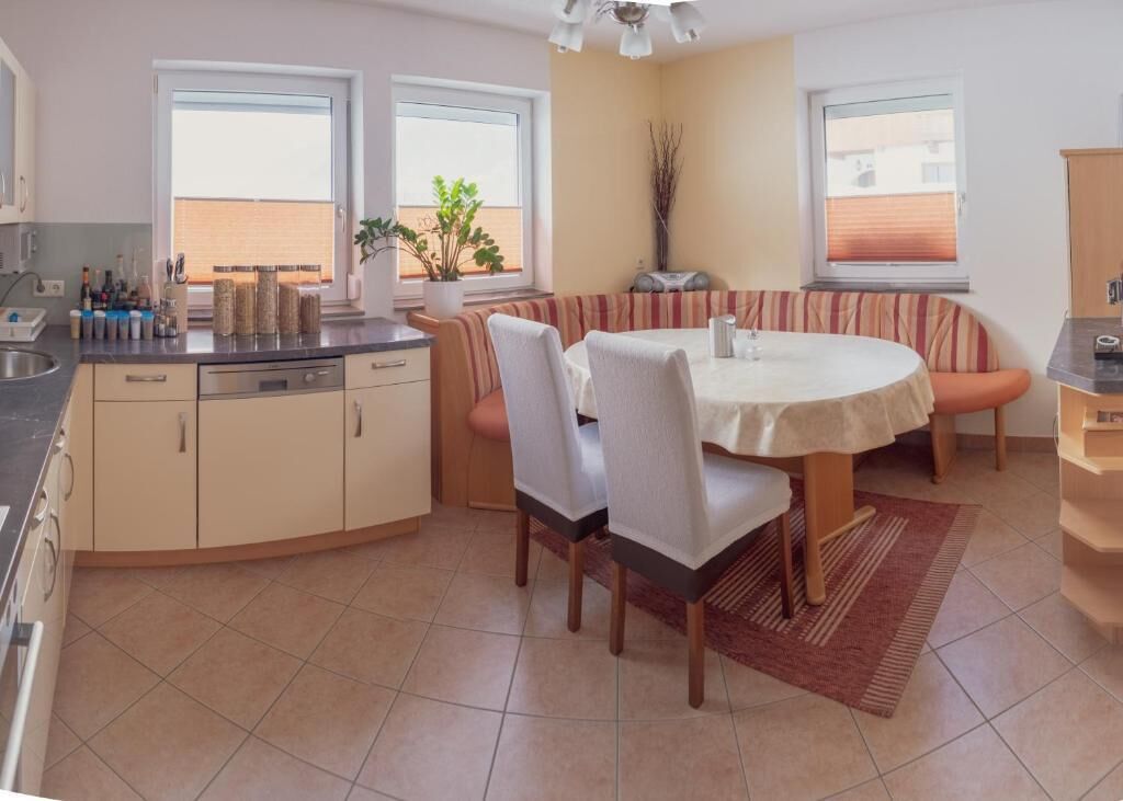 Een compacte keuken met een eethoek, met een ronde tafel, stoelen en een ingebouwde bank.