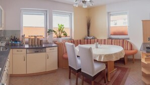 A compact kitchen with a dining area, featuring a round table, chairs, and a built-in bench. - Vacation cottage Maric (Oetz)