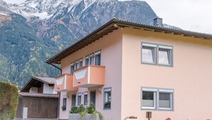A two-story building with a balcony, a garage, and a mountain backdrop. - Vacation cottage Maric (Oetz)