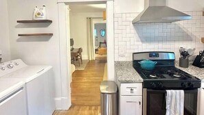 Uma cozinha com fogão de aço inoxidável, forno e máquina de lavar branca.