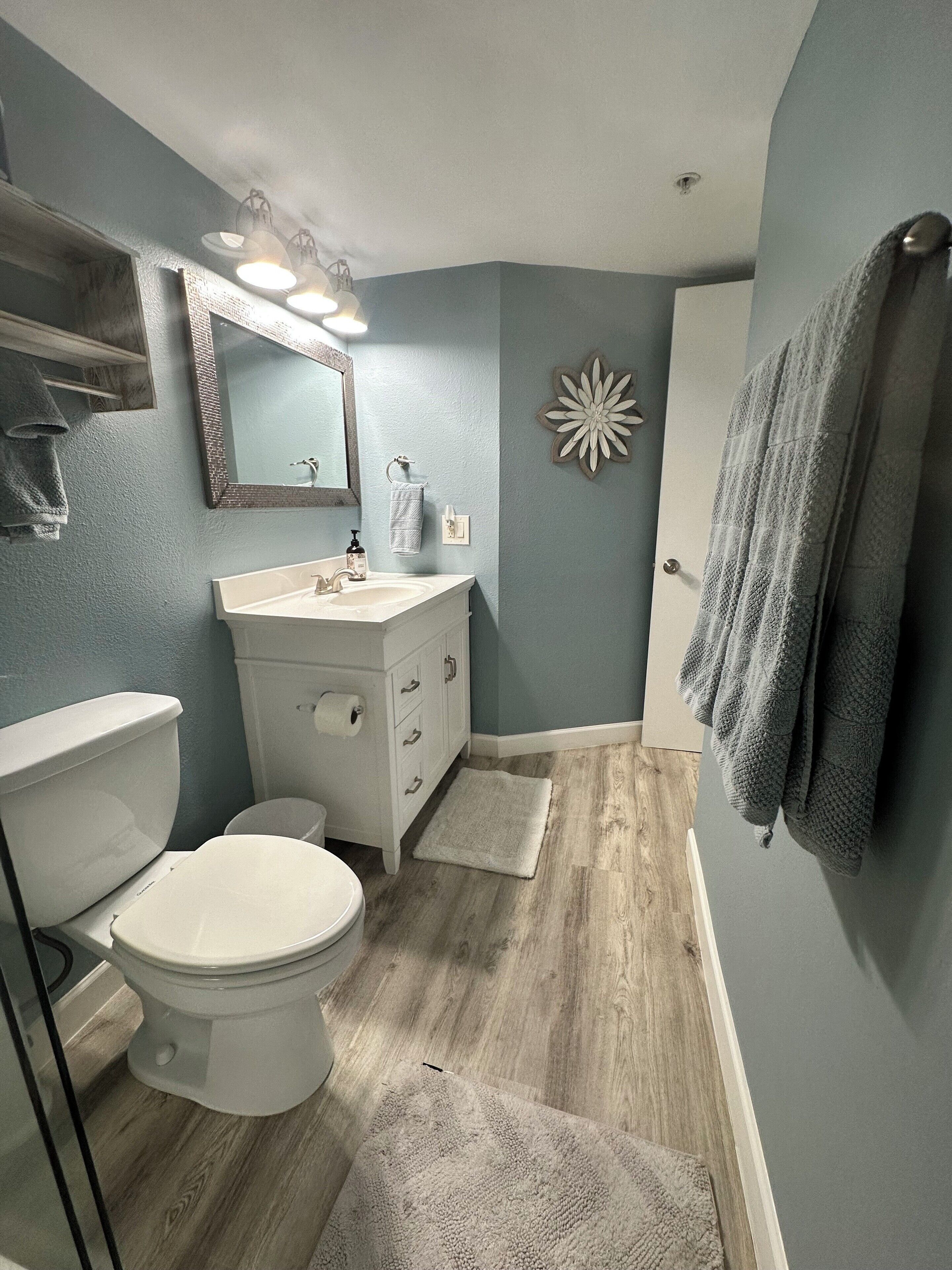 A bathroom with a toilet, sink, and mirror.