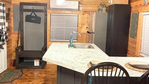 A compact kitchen with a marble countertop, wooden cabinets, and a ceiling fan.