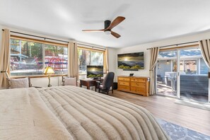 A bedroom with a large bed, a desk, a chair, a dresser, and a ceiling fan.