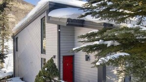 Un bâtiment moderne avec une porte rouge et des environs recouverts de neige.