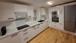 Una cucina moderna con mobili bianchi, un piano di lavoro nero, un frigorifero in acciaio inossidabile, un forno e un microonde.