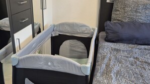 Ein Zimmer mit einem Bett, einem kleinen Tisch, einem Stuhl und einem an der Wand montierten Fernseher.