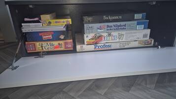 A shelf with various board games, including 'Domino', 'Mille Grazi', and 'Professors'.