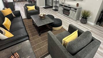 Un salon moderne avec des canapés gris, une table basse et un téléviseur à écran plat fixé au mur.