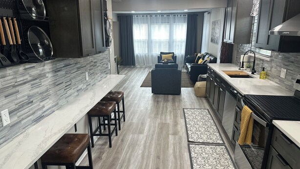 A modern kitchen with a marble countertop, dark wooden stools, and a built-in oven. - Stylish 2Bdrm in perfect location-close to Kyle Field & Midtown Park (Bryan)