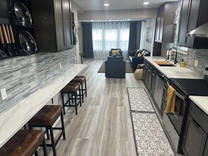 A modern kitchen with a marble countertop, dark wooden stools, and a built-in oven. - Stylish 2Bdrm in perfect location-close to Kyle Field & Midtown Park (Bryan)