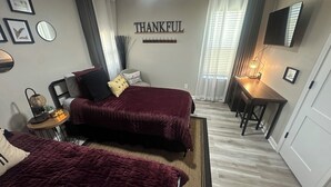 A bedroom with two beds, a bedside table, a wall clock, a mirror, and a 'THANKFUL' sign. - Stylish 2Bdrm in perfect location-close to Kyle Field & Midtown Park (Bryan)