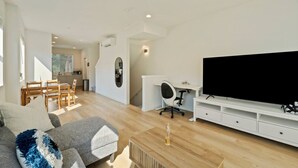 Una sala de estar moderna con sofá, televisor y comedor.