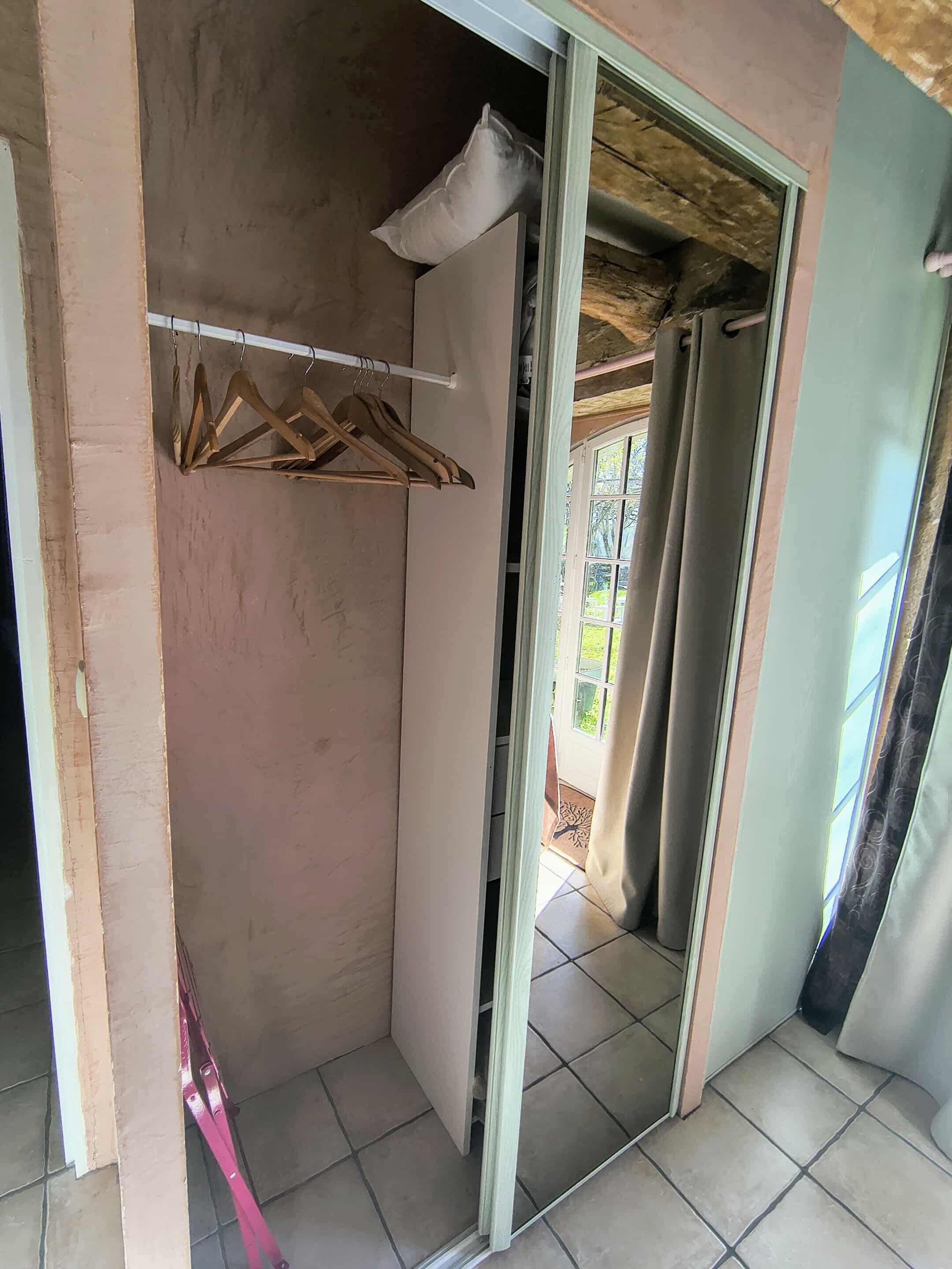 A room with a wooden hanger rack, a partially open door, and a tiled floor.