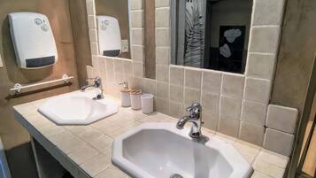 Baño con dos lavamanos, un secador de manos y un espejo.
