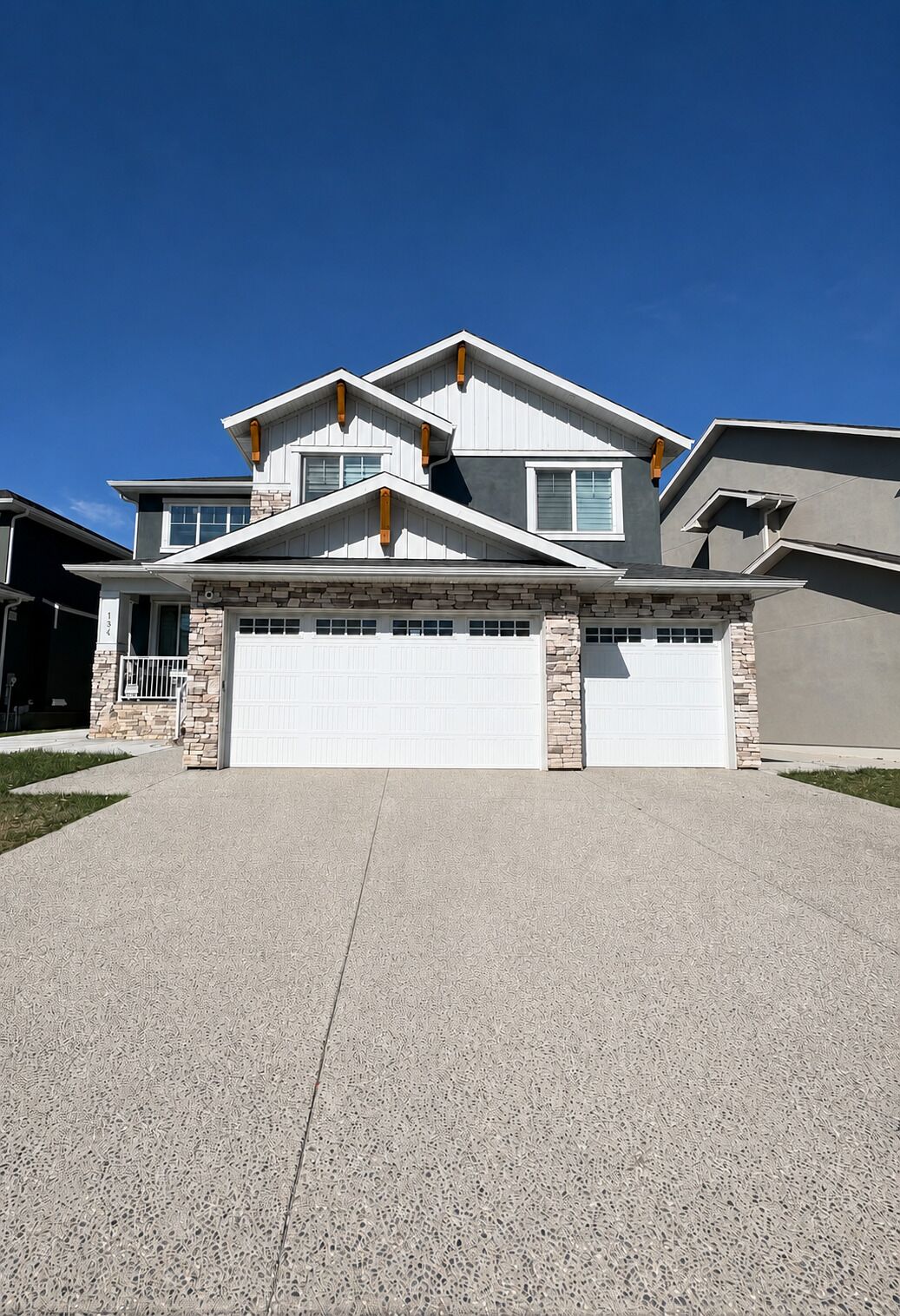 Une maison à deux étages avec une façade en pierre, un garage et un ciel dégagé.