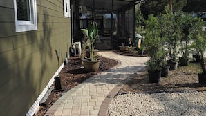A house with a covered patio, a brick pathway, and potted plants.