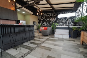 Uma cozinha moderna com área de bar, um sofá cinzento e parede estampada.