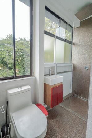 Casa de banho com sanita, lavatório e zona de duche.