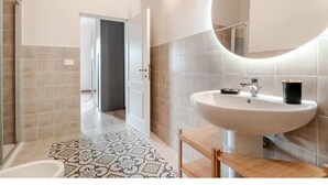 A modern bathroom with a large sink, a mirror, and a patterned floor.