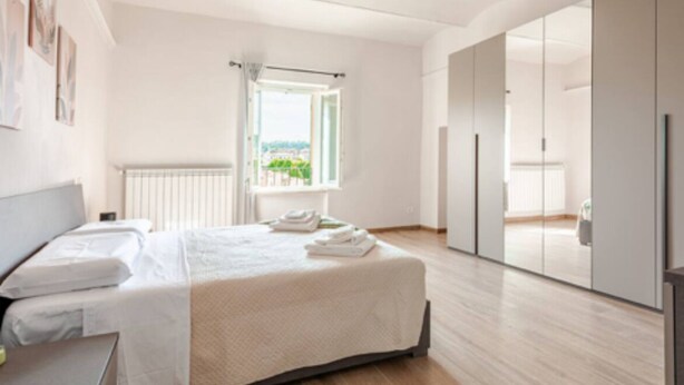 A modern bedroom with a large bed, a window with a view, and a sliding door closet.