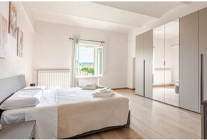 Ein modernes Schlafzimmer mit einem großen Bett, einem Fenster mit Aussicht und einem Schiebetürenschrank.