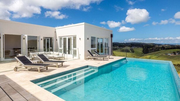 A modern house with a swimming pool, sun loungers, and a scenic view. - Onetangi Estate including guest cottage by Waiheke Pure - Luxurious italian style palazzo with pool, hot tub and  expansive views (Onetangi)