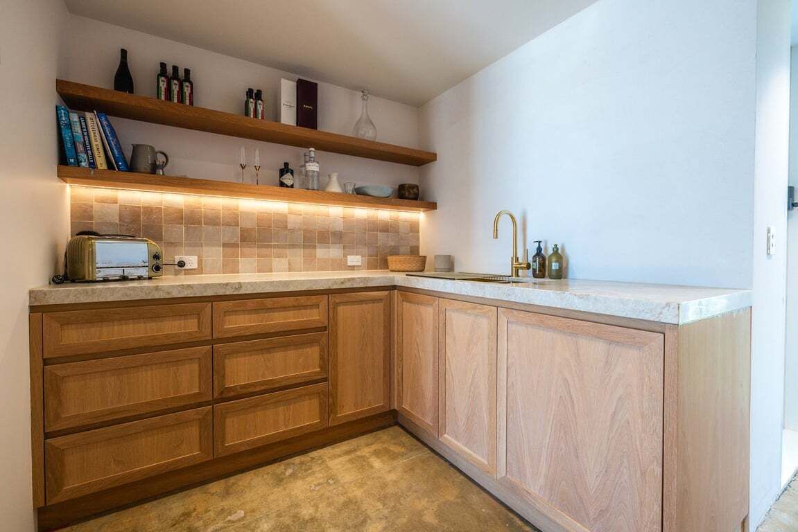 A modern kitchen with wooden cabinets, a built-in oven, and a countertop with a toaster.