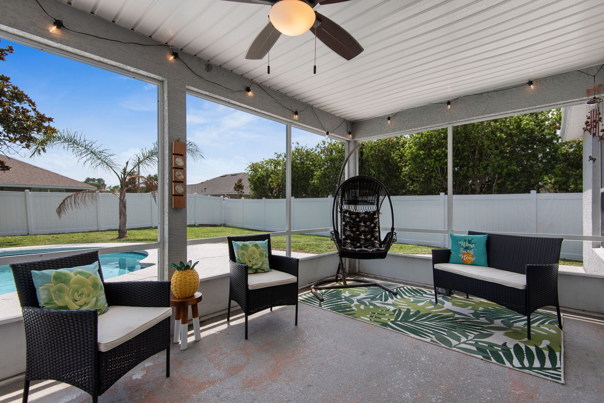 A covered patio area with outdoor furniture, a ceiling fan, and a view of a swimming pool.