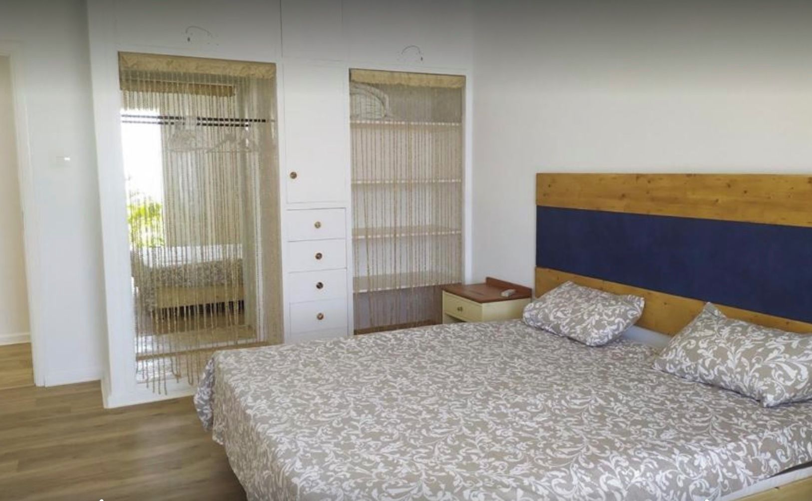 Una camera da letto con un letto, una testiera in legno, un comodino e un armadio con uno specchio.