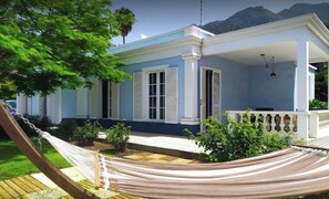 Ein zweistöckiges Haus mit Veranda, einer Hängematte und Blick auf die Berge.