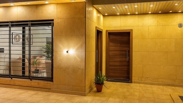 Une façade d’immeuble avec une grande fenêtre en verre, une plante en pot et une porte en bois.