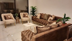 Un salon moderne avec un canapé marron, deux fauteuils, une table basse et des plantes en pot.