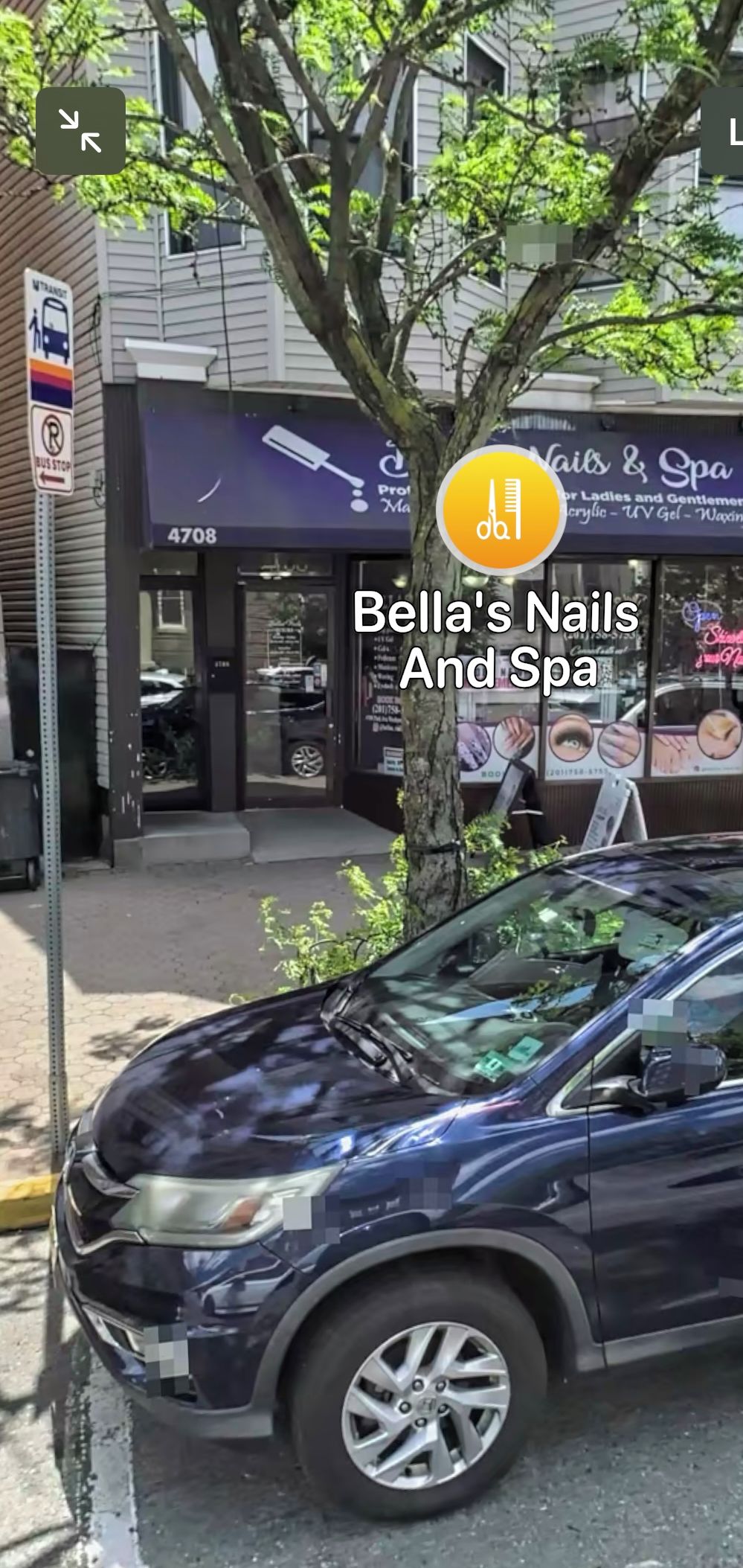 A storefront with a sign for 'Bella's Nails & Spa' and a bus stop sign nearby.