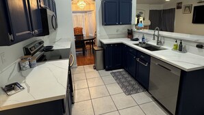 A modern kitchen with dark cabinets, a white countertop, and a tiled floor.