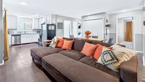 Un apartamento moderno con un sofá marrón, una mesa de comedor y una zona de cocina.