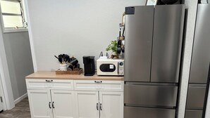 Cocina moderna con armarios blancos, microondas y refrigerador de acero inoxidable.